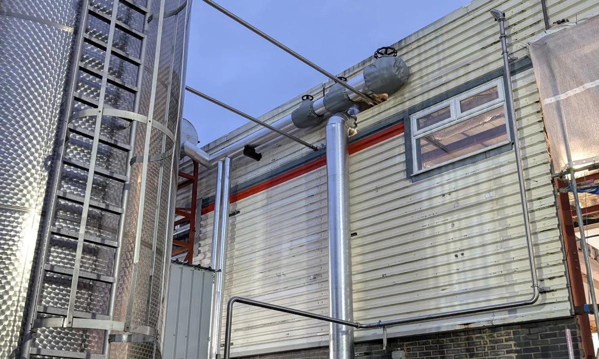 External metal-clad steam pipework serving a commercial food production facility
